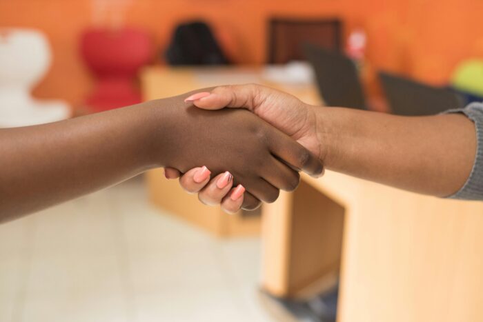 pexels photo 955388 955388 Two women exchanging a handshake in a professional indoor office setting.